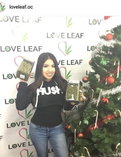 A woman holding up her phone in front of a christmas tree.