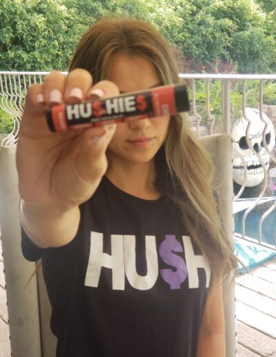 A woman holding up a candy bar in front of her face.