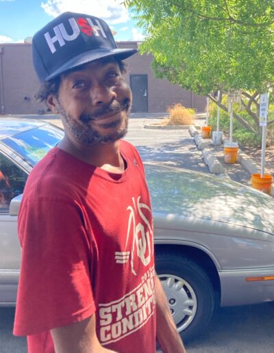 A man standing next to a car on the street.