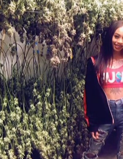 A woman standing next to some plants in the street.