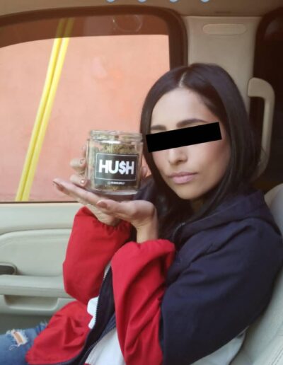 A woman holding a jar of hush in her hand.