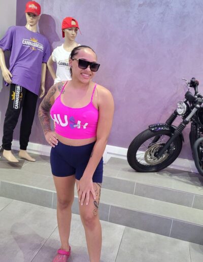 A woman in pink shirt and shorts standing next to two mannequins.